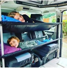 two children laying in the back of a van with luggage on it's sides