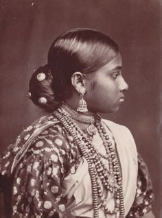 an old black and white photo of a woman with jewelry on her neck, wearing a headdress