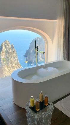 a bath tub sitting in front of a window next to a sink with soap bottles on it