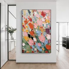 an abstract painting hangs on the wall in a white room