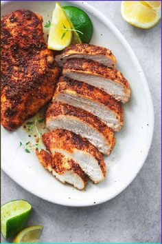 sliced chicken on a white plate with lemons and limes next to the dish