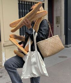 a person sitting on a curb with bread in their hands and a bag full of them