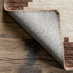 an area rug on top of a wooden floor next to a white and brown rug