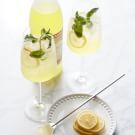 a table topped with glasses and plates filled with lemonade next to bottles of alcohol