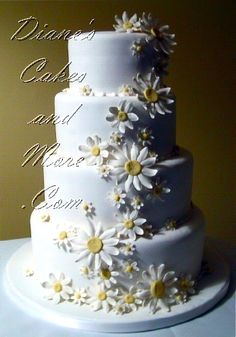 a white wedding cake with daisies on it