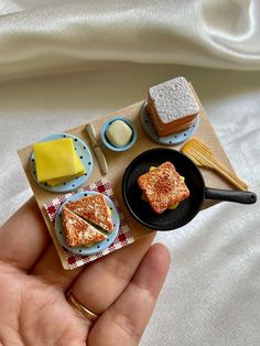 a person holding a plate with toast and butter on it next to other food items