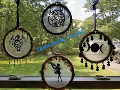 three glass ornaments hanging from a window sill in front of a grassy area with trees