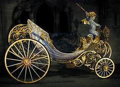 a gold and white horse drawn carriage in front of a castle