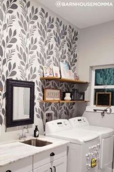 a white washer and dryer sitting next to each other in a room with wallpaper