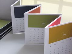 three calendars sitting on top of a table next to each other