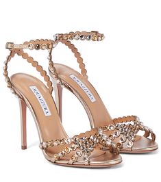 a pair of high heeled shoes with pearls and bows on the toes, all in gold