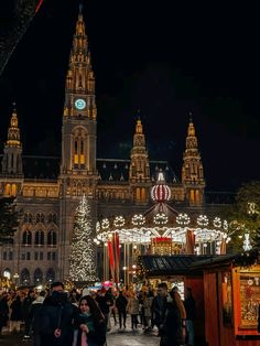 people are walking around in front of a large building with christmas lights on the side