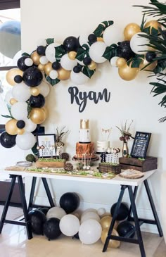 a table topped with cake and balloons next to a sign that says ryan on it