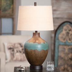 a table with a lamp on top of it next to a couch in a living room