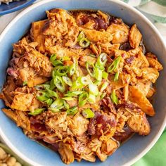 a bowl filled with meat and vegetables on top of a green table cloth next to other food