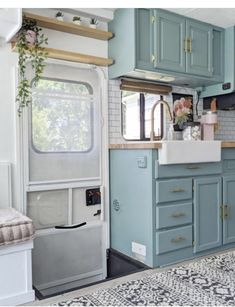 a kitchen area with blue cabinets and white tile on the walls, along with a rug