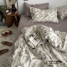 an unmade bed with a book on it and some shoes scattered around the bed