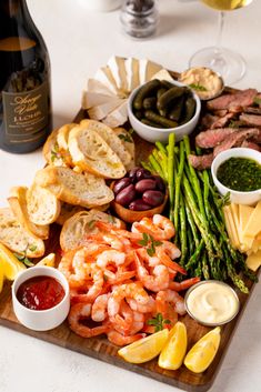 a wooden platter filled with different types of food next to a bottle of wine