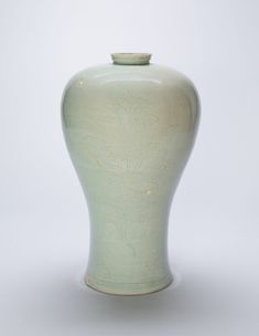 a green vase sitting on top of a white table