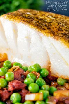 a fish fillet is on a plate with peas and potatoes in the foreground