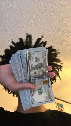 a person with dreadlocks holding money in front of their face