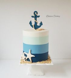 there is a blue and white cake with an anchor on the top that has sand around it