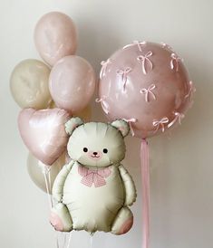 a white teddy bear sitting on top of balloons