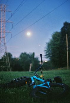 a blue bicycle laying on the ground with power lines in the background at night time