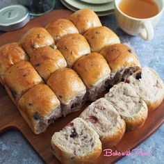 rolls cut in half on a cutting board next to a cup of tea