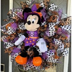 a mickey mouse wreath on the front door with polka dots and pumpkins around it