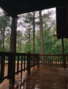 a wooden deck in front of trees with rain falling on the ground and it's raining