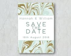 save the date card with gold and white marble pattern on it, in front of a gray background