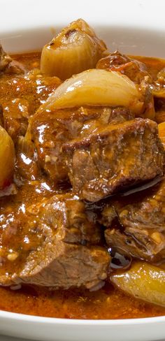 a white bowl filled with stew and potatoes