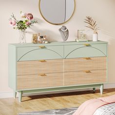 a bedroom with a dresser, mirror and flowers on the sideboard in front of it