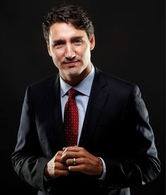 a man in a suit and tie posing for the camera with his hands clasped together