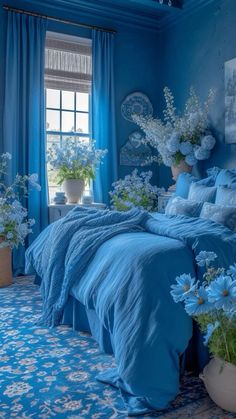 a bedroom with blue walls and flowers in vases on the bed, along with curtains