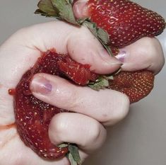 a person holding two strawberries in their hands