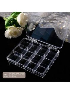 clear acrylic jewelry box with compartments and flowers on the table next to it