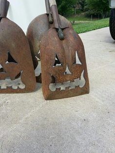 two rusty metal jack - o - lantern pumpkin heads are sitting on the cement outside