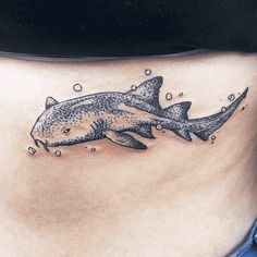 a woman's stomach with a tattoo of a shark and bubbles on the side