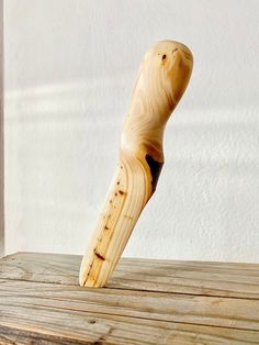 a wooden object sitting on top of a wooden table next to a white wall,