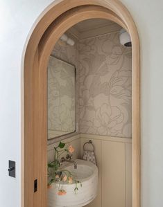 an arched doorway leading to a bathroom with a sink and mirror on the wall next to it