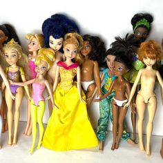 a group of barbie dolls standing next to each other on a white surface in front of a wall