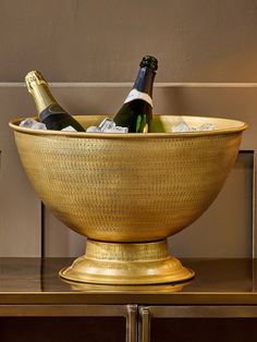 two bottles of champagne in a golden bowl