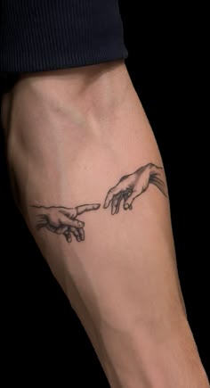 the creation of man's hands tattoo on the left forearm and right hand behind him