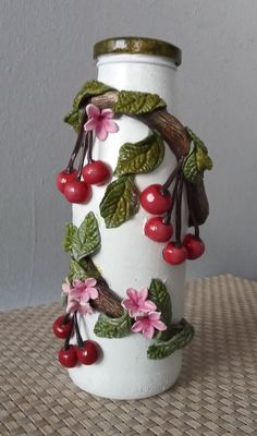 a white vase with cherries and leaves on it