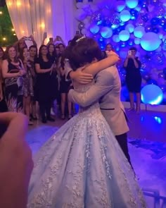 the bride and groom are hugging each other in front of their wedding party on the dance floor