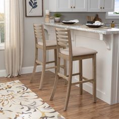 a kitchen with two stools and a bar in the middle, next to a window