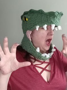 a woman wearing a green crocheted hat with an alligator's head on it