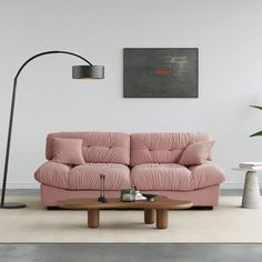 a living room with a pink couch and coffee table in front of a painting on the wall